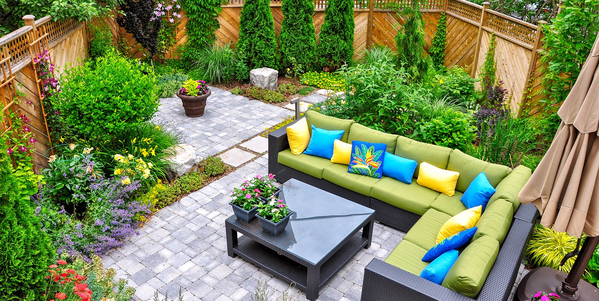 Gemütliche Gartenterrasse mit Couch, Tisch und Sonnenschirm, perfekt für gesellige Zusammenkünfte im Freien.